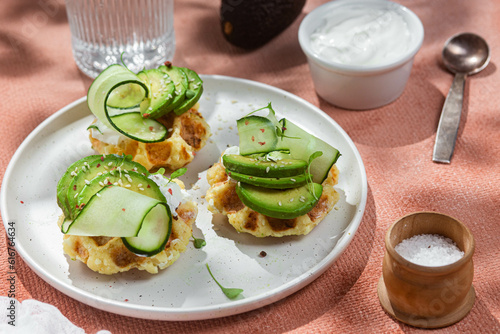 Waffles with cream cheese, avocado and cucumber on a plate