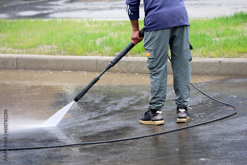 Worker watering the sidewalk with a hose. Street cleaning and disinfection in summer city