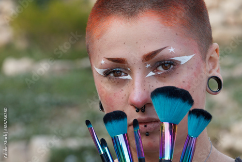 Retrato facial de una mujer hermosa joven con maquillaje elegante y pinceles de maquillaje coloridos que cubren su rostro. photo