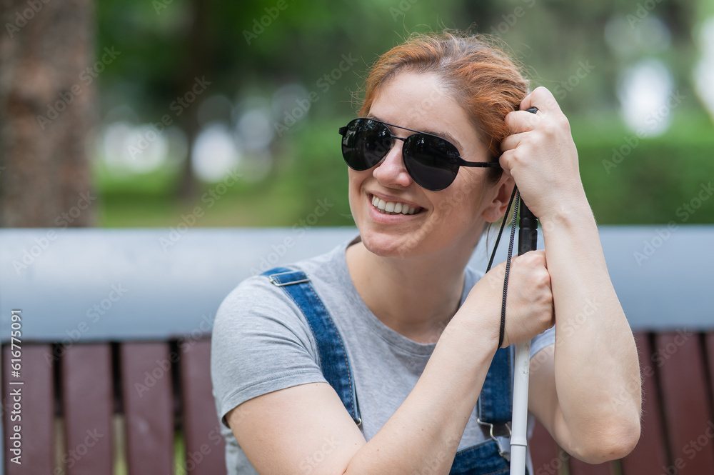 Blind red-haired woman sitting outdoors leaning on a cane. Blind red-haired woman sitting outdoors leaning on a cane.