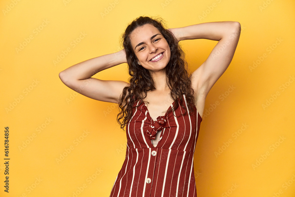 Young Caucasian woman, yellow studio background, stretching arms, relaxed position. Young Caucasian woman, yellow studio background, stretching arms, relaxed position.