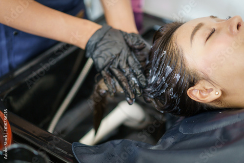 Close up shoot of Asian beautiful woman get hair washing and caring at professional salon shop.