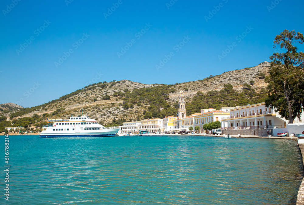 Symi also known as Syme or Simi is a Greek island one of the Dodecanese islands. Village of Panormitis on island of Symi in Greece. Holy Monastery of the Taxiarch Michael Panormitis on the background.