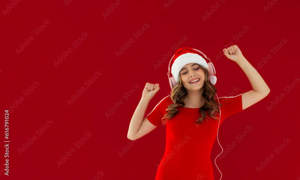 Funny young woman wearing green hoodie Christmas hat listening music with headphones keeping eyes closed isolated on red background studio portrait. Happy New Year celebration merry holiday concept Funny young woman wearing green hoodie Christmas hat listening music with headphones keeping eyes closed isolated on red background studio portrait. Happy New Year celebration merry holiday concept