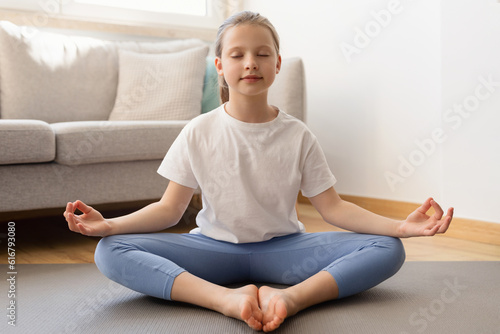 Serious teen caucasian teenage girl in sportswear with closed eyes meditation, practices yoga, enjoy relax
