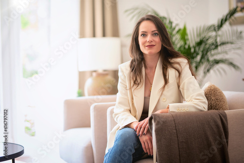 Obraz na plátně Portrait of brunette haired young woman relaxing in an armchair at the modern ho