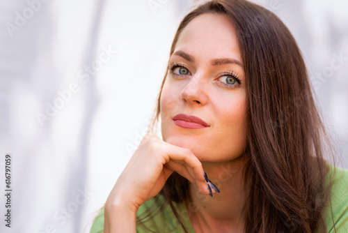 Headshot of young woman with beautiful green eyes and brunette hair sitting in the sun