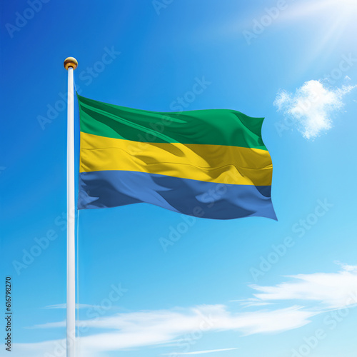 Waving flag of Gabon on flagpole with sky background.