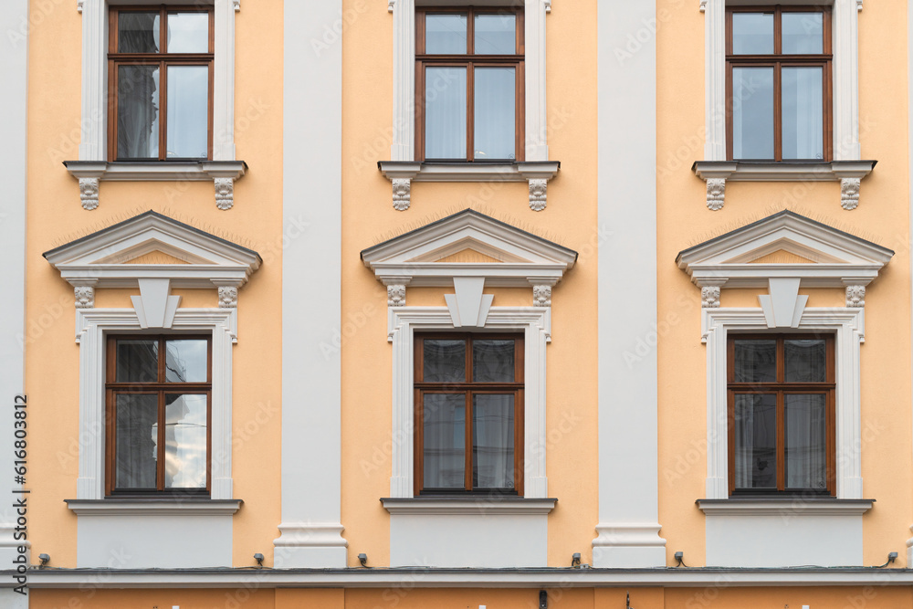 Wooden windows on yellow walls. Facade of a European antique city building.