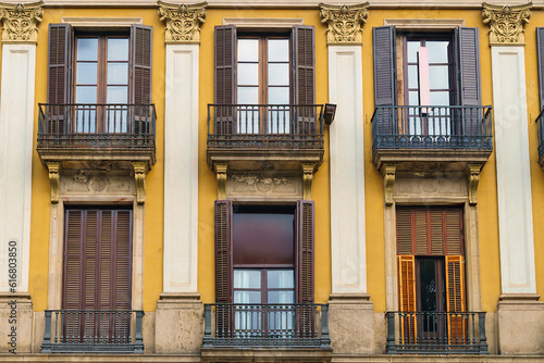 Wooden windows with shutters on yellow walls. Facade of a European antique city building.