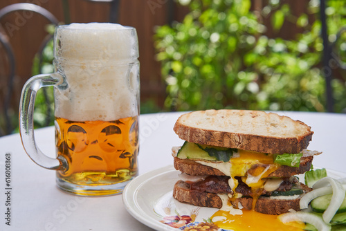 Close up picture of variation on Club sandwich with pint of czech pilsner beer, the best beer in the world. Light and tasty lunch served outside in the garden restaurant during summer sunny lunchtime.