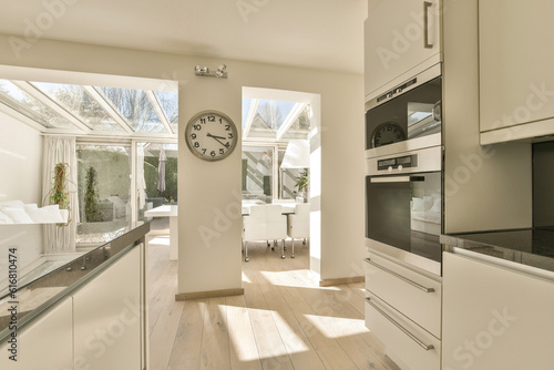 a kitchen area with a clock on the wall and an oven in the corner next to the counter is white