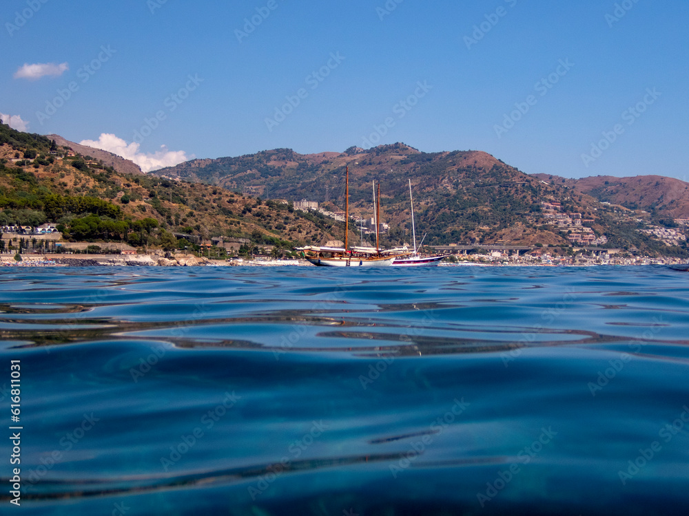 Fototapeta premium Barca a vela nella baia dell'isola di Sirene a Taormina