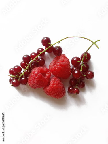 raspberries and bunches of red currants on a white background