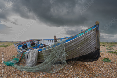 net draped over an abandoned fishing boat on the beach