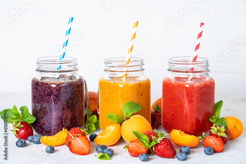 Smoothie with fresh fruits and berries at white background. Smoothie set in jars.