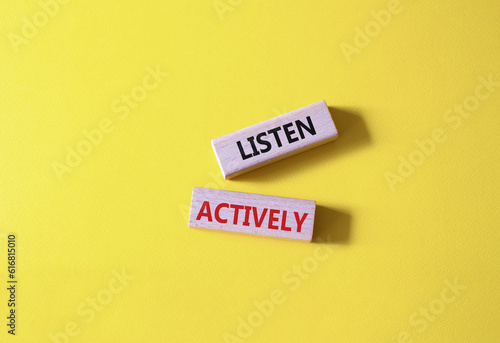 Listen actively symbol. Wooden blocks with words Listen actively. Beautiful yellow background. Business and Active listening concept. Copy space.