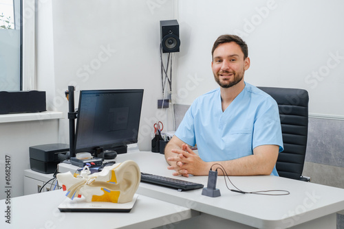 Otolaryngologist at modern mediccal center. Portrait of audiologist who assess disorders of hearing. Ear model on the table. Copy sapce photo