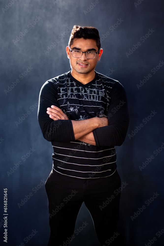 Latin male model posing in front of camera. Attractive latino man wearing dark clothing.