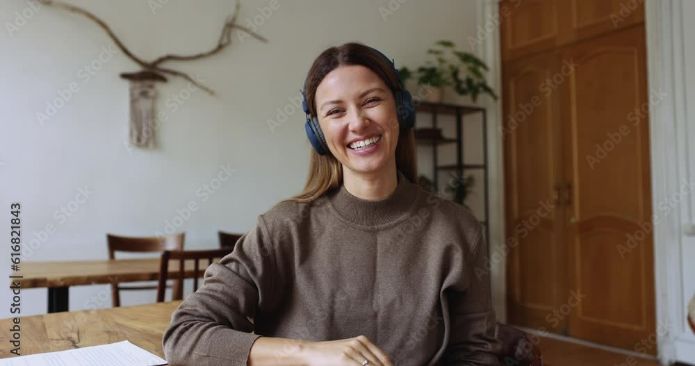 Young woman in headphones start videocall event sit at desk in office, smile look at camera, greeting client or friend, enjoy virtual meeting by personal or business, pass remote job interview use app Young woman in headphones start videocall event sit at desk in office, smile look at camera, greeting client or friend, enjoy virtual meeting by personal or business, pass remote job interview use app