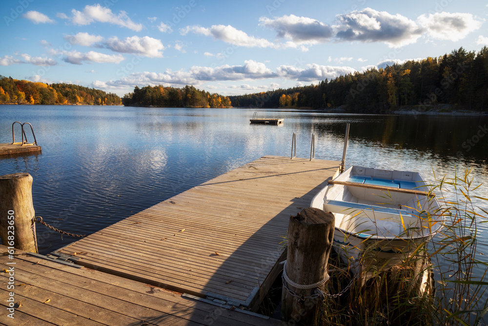 Wooden jetty and a boat near the shore of the lake on an autumn day