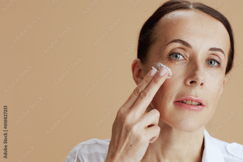 modern female with facial cream on face on beige background modern female with facial cream on face on beige background