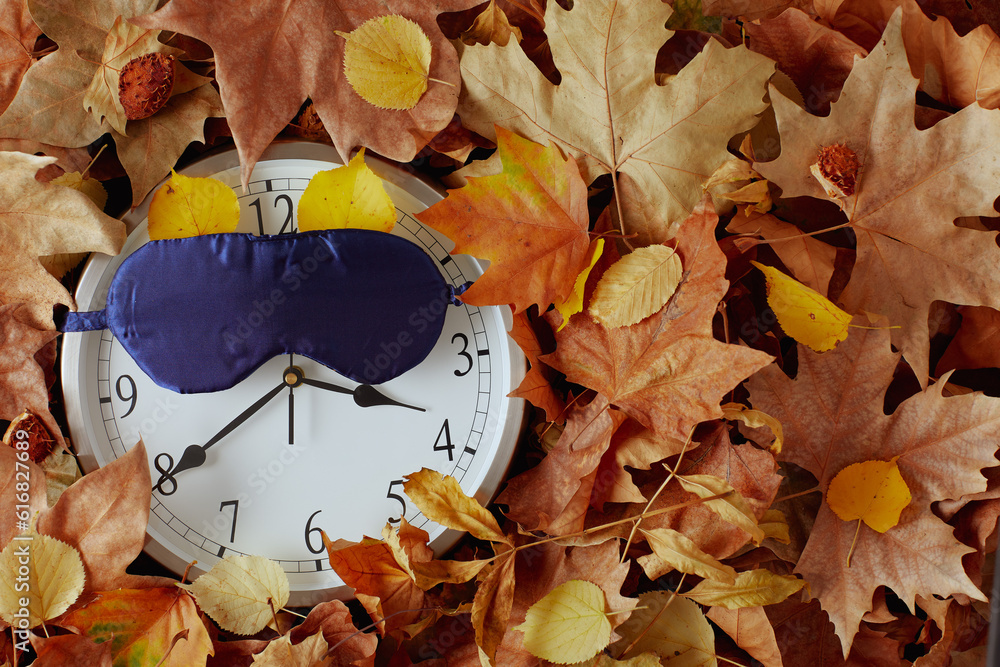 autumn background with clock, sleeping mask and leaves - obrazy, fototapety, plakaty 