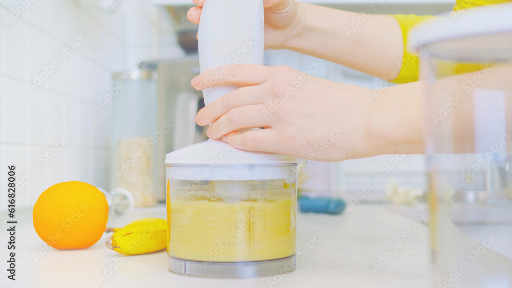 In a kitchen, a young woman prepares a healthy smoothie using a blender. Surrounding her are fresh fruits, including sliced pineapple on a wooden cutting board. nutrition and healthy eating.