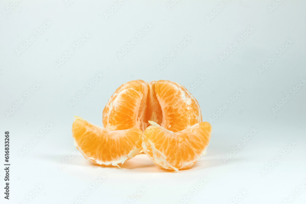 close-up of a tangerine with various wedge  next to it on a white background