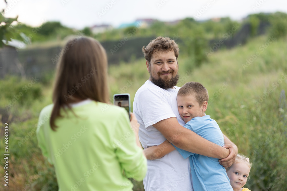 Woman photographing her husband with children Woman photographing her husband with children