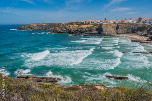 Cliff with herbs with aerial view to waves and turquoise sea of Zambujeira do Mar beach, Alentejo PORTUGAL photo