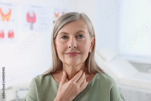 Endocrine system. Senior woman doing thyroid self examination indoors