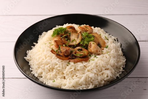 Delicious rice with parsley and mushrooms on white wooden table, closeup