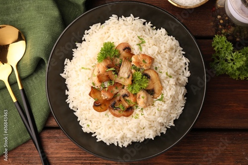 Delicious rice with mushrooms and parsley served on wooden table, flat lay