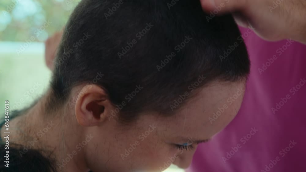 Young man using hair clippers and shaving hair of his girlfriend, doing haircut during daytime at home. Close-up shot Young man using hair clippers and shaving hair of his girlfriend, doing haircut during daytime at home. Close-up shot