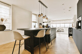 a kitchen and dining area in a modern home with wood flooring, white walls, black cabinets and large windows