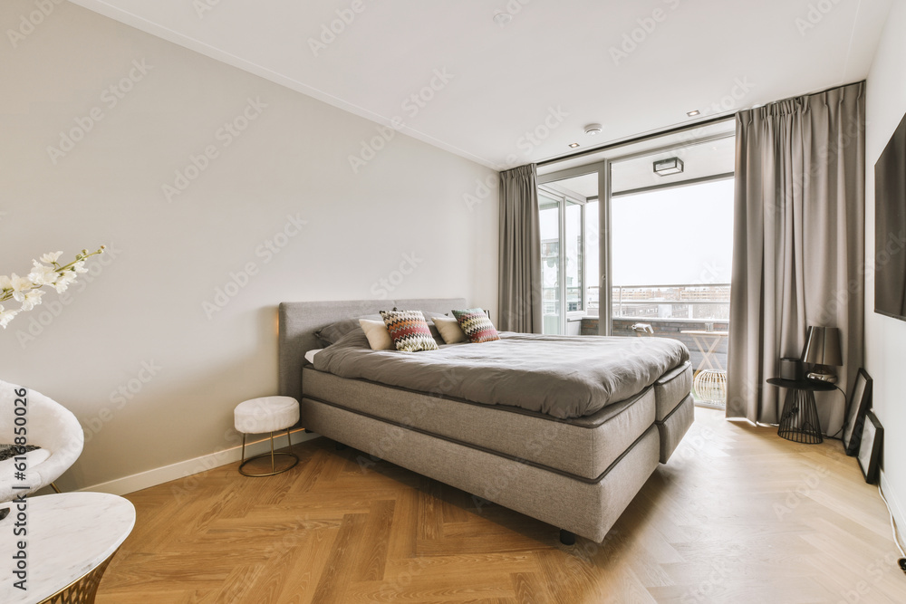 a bedroom with hardwood flooring and large windows overlooking the cityscapet is in front of the bed