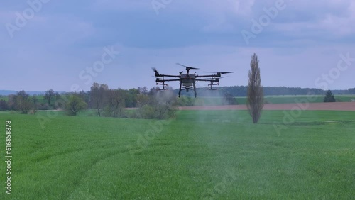 Professional Agriculture Drone Flying and Spraying Fertilizer Over Green Farming Field photo