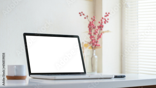 Mock up laptop computer  coffee cup and potted plant on white table. Empty screen for your advertise text.