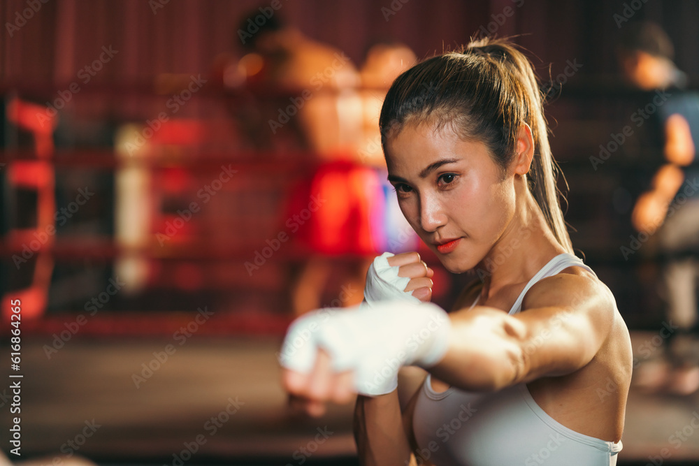Asian woman training kick boxing with punching glove, fitness woman with physical exercising trainer by doing self defense workout or fitness activity in a wellness gym. Determined strong fighter