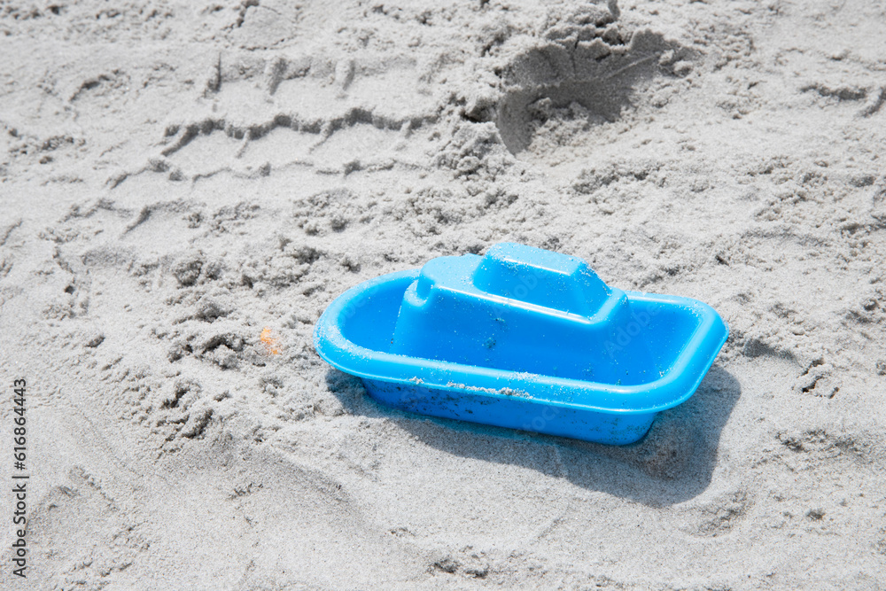 abandoned blue toy boat on the sand at the beach, not being played with, copy space abandoned blue toy boat on the sand at the beach, not being played with, copy space