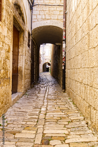Narrow street with stone houses. Old houses and old narrow alley in Trogir  Croatia  Europe. Streets in old town.