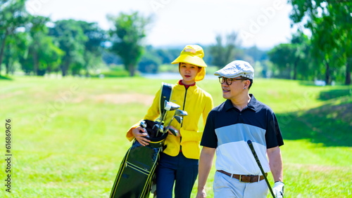 Foto Asian man golfer walking together with female caddy on fairway at country club golf course