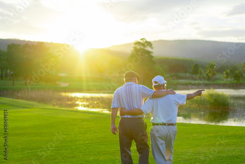 Happy Asian senior man friends golfing on golf course fairway together at country club. Healthy elderly people golfer enjoy outdoor lifestyle leisure activity golf sport on summer holiday vacation.