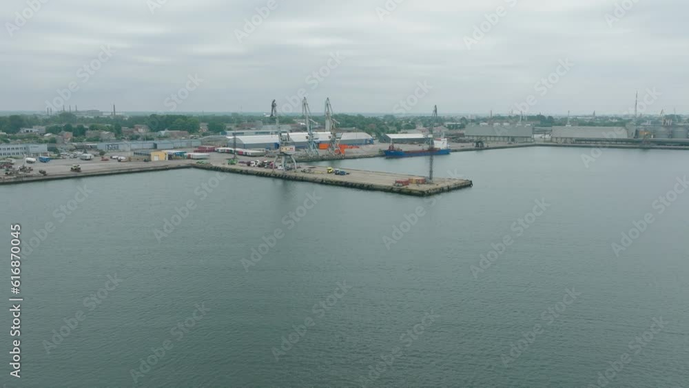 Aerial establishing view of port cranes and empty loading docks at Port Of Liepaja (Latvia), Liepaja city in the background, overcast summer day, wide drone shot moving forward, tilt down Aerial establishing view of port cranes and empty loading docks at Port Of Liepaja (Latvia), Liepaja city in the background, overcast summer day, wide drone shot moving forward, tilt down