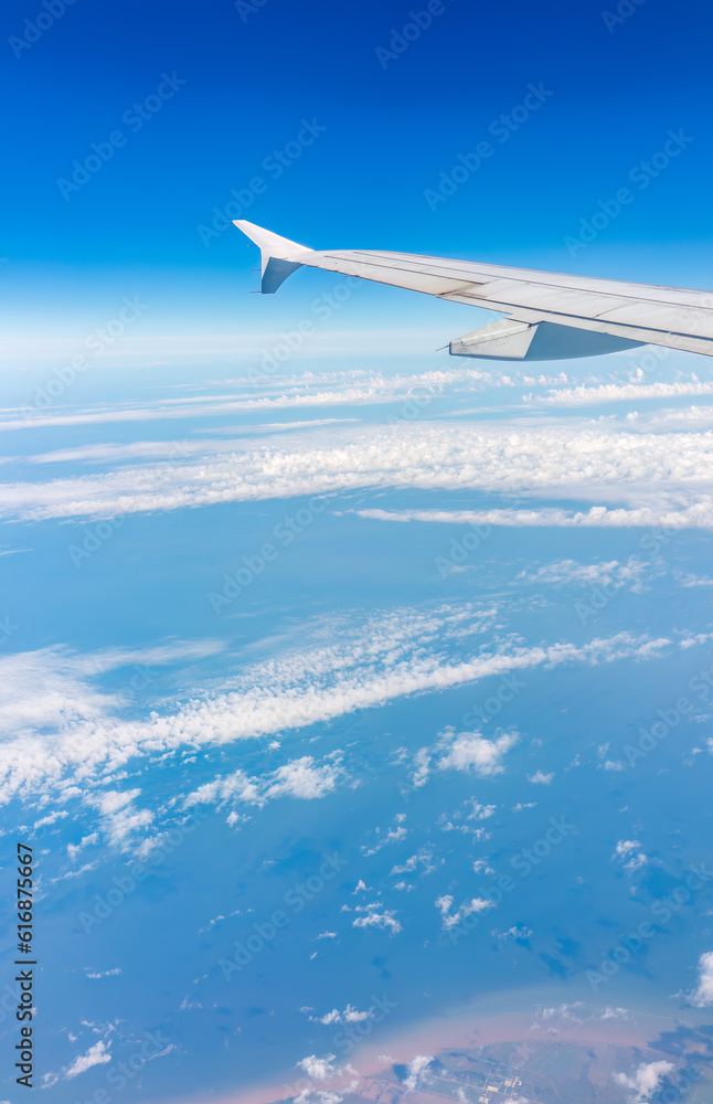 View from the airplane window at a beautiful cloudy sky and the airplane wing