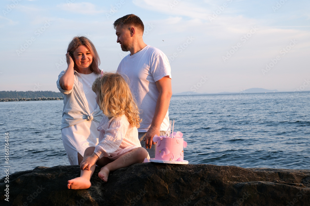 husband and wife with their daughter at the sea celebrate the third anniversary of a small child Love and happiness in the family tenderness of mutual understanding Friendship middle age