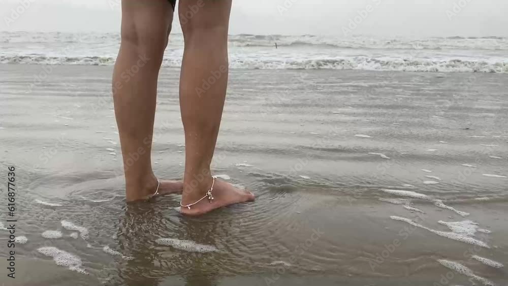 Waves hitting the legs of an Indian girl standing in the beach. No face video. Waves hitting the legs of an Indian girl standing in the beach. No face video.