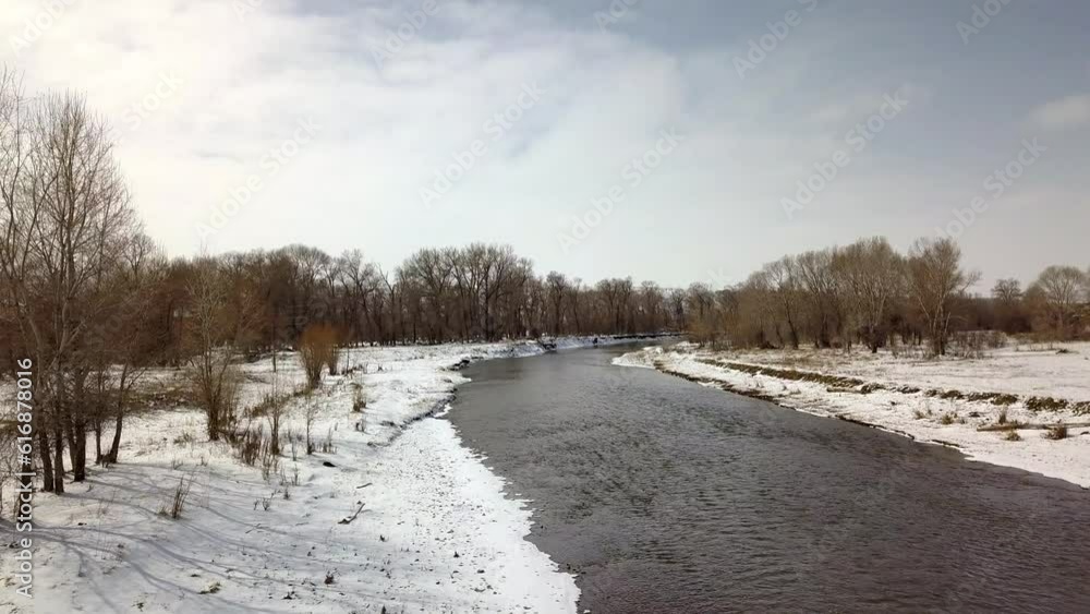 Aerial: Drone Flying Forward Over River Amidst Snow And Bare Trees In Forest Against Cloudy Sky - Billings, Montana Aerial: Drone Flying Forward Over River Amidst Snow And Bare Trees In Forest Against Cloudy Sky - Billings, Montana