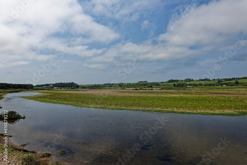 The exposed Mudflats and Pebbles at low tide at the River North Esk near to its Mouth at the North Sea, with Eskview Farm and caravan Park in the background.